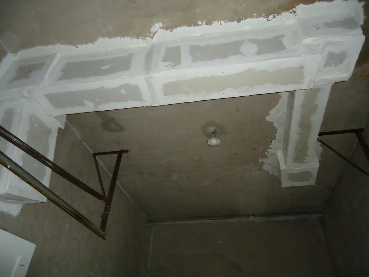 looking up at new drywall boxing along a garage ceiling, with the seams taped and spackled but not yet painted